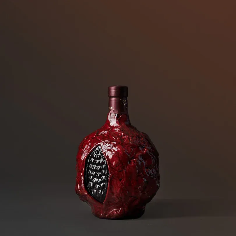 Hand-painted pomegranate wine bottle on a dark surface