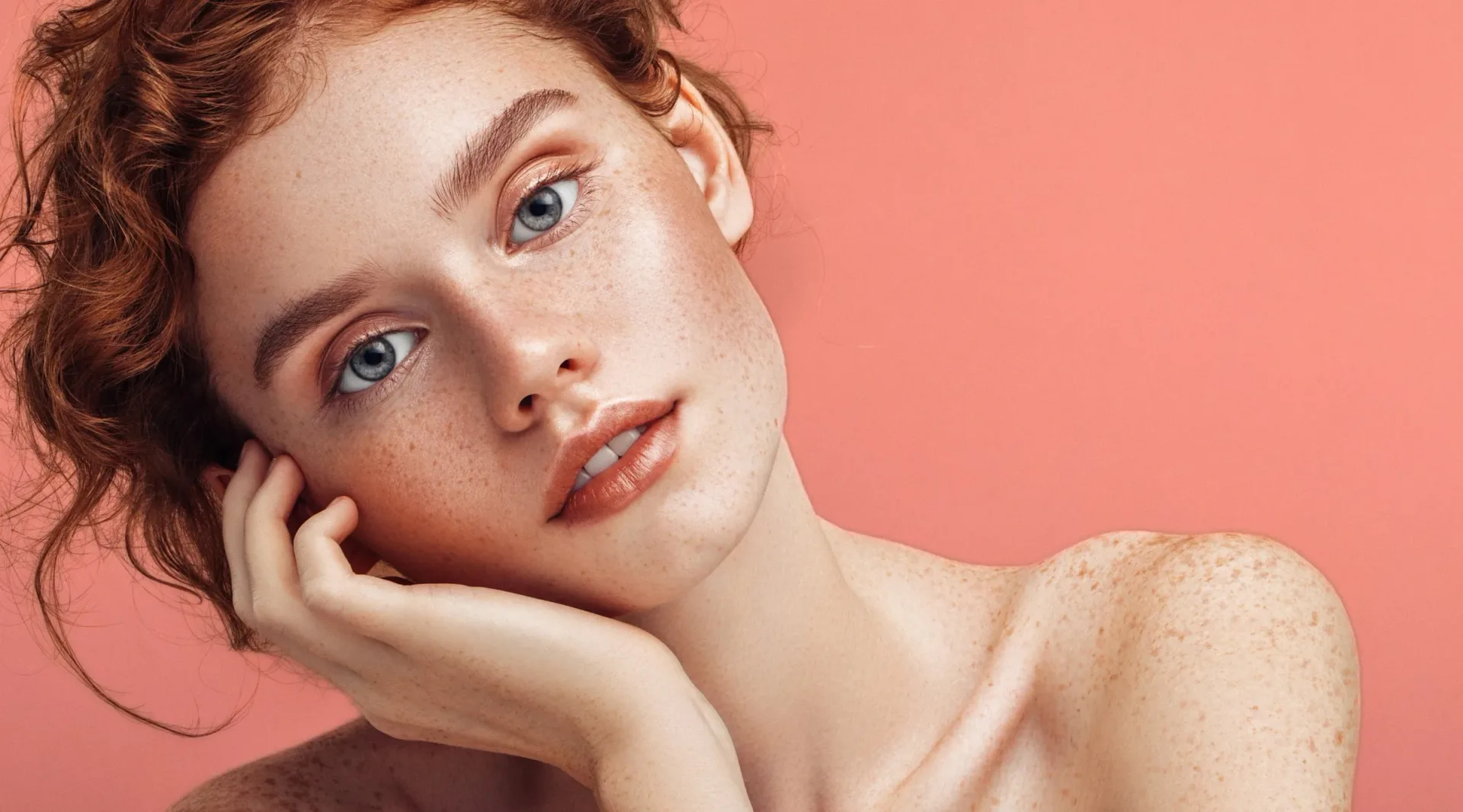 Oz Lab campaign portrait of a freckled model on a coral background