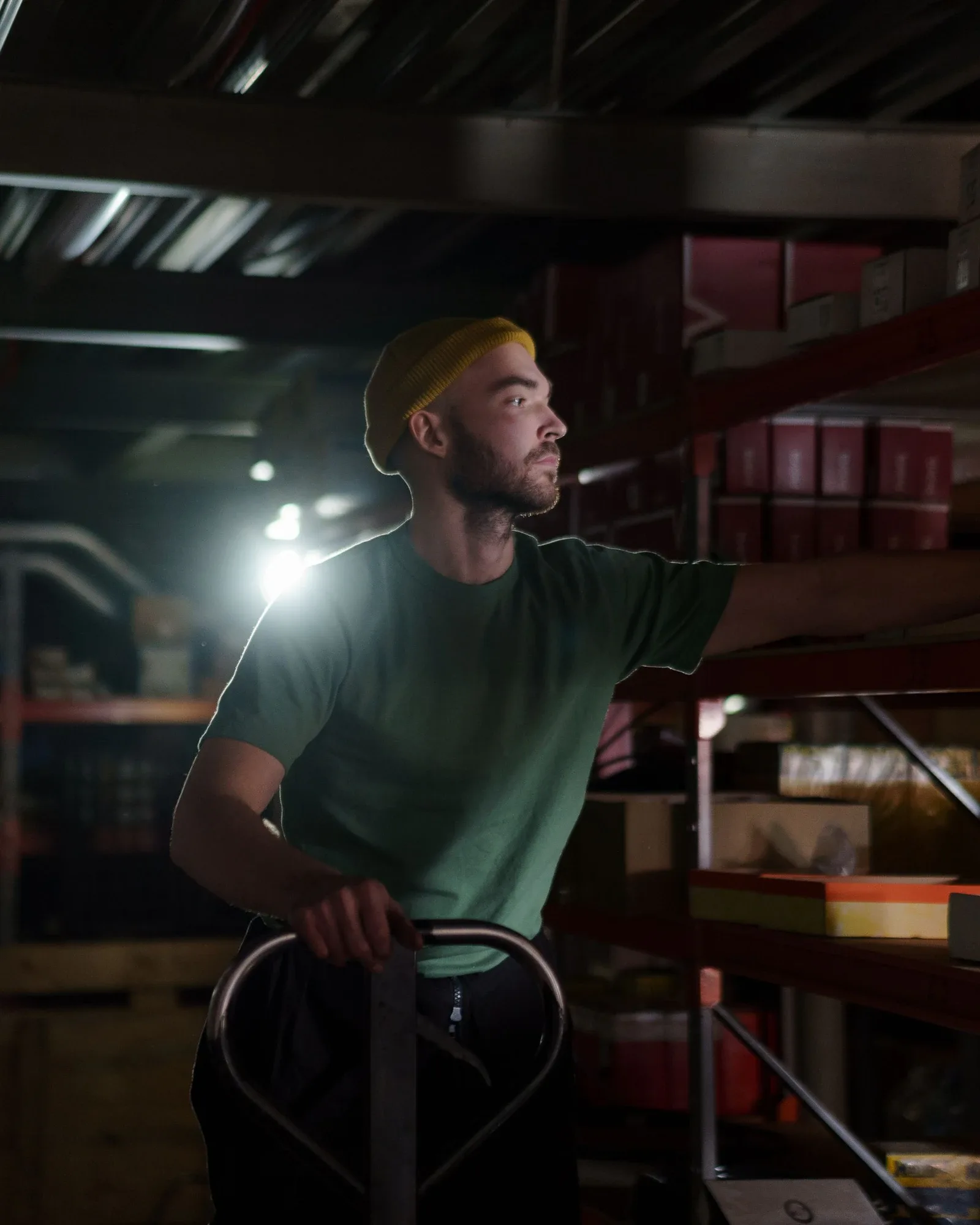 A warehouse worker pulling a pallet jack through a dim aisle